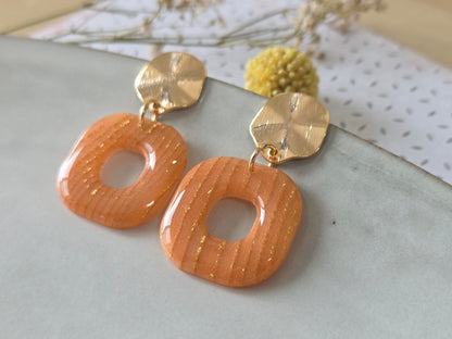 Detail van Terracotta Poort oorbellen met houtnerftextuur en goudspikkels