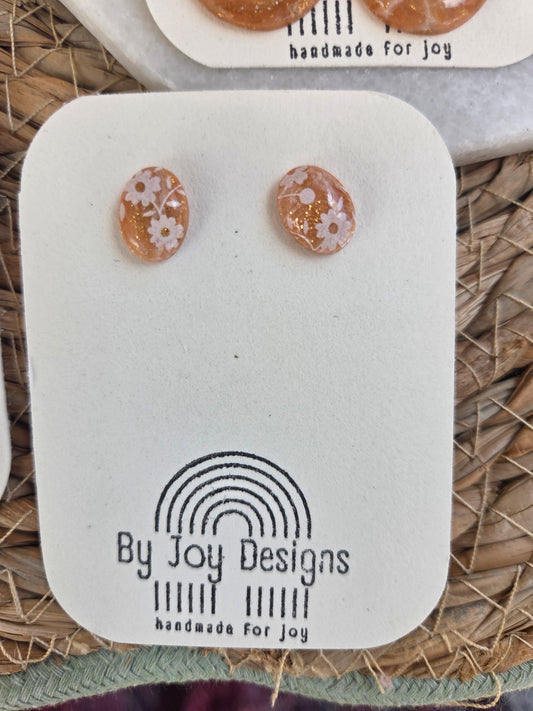 Perzik Bloesemknop ovale oorstekers met witte bloemen en gouden glitterdeeltjes op een By Joy Designs kaartje