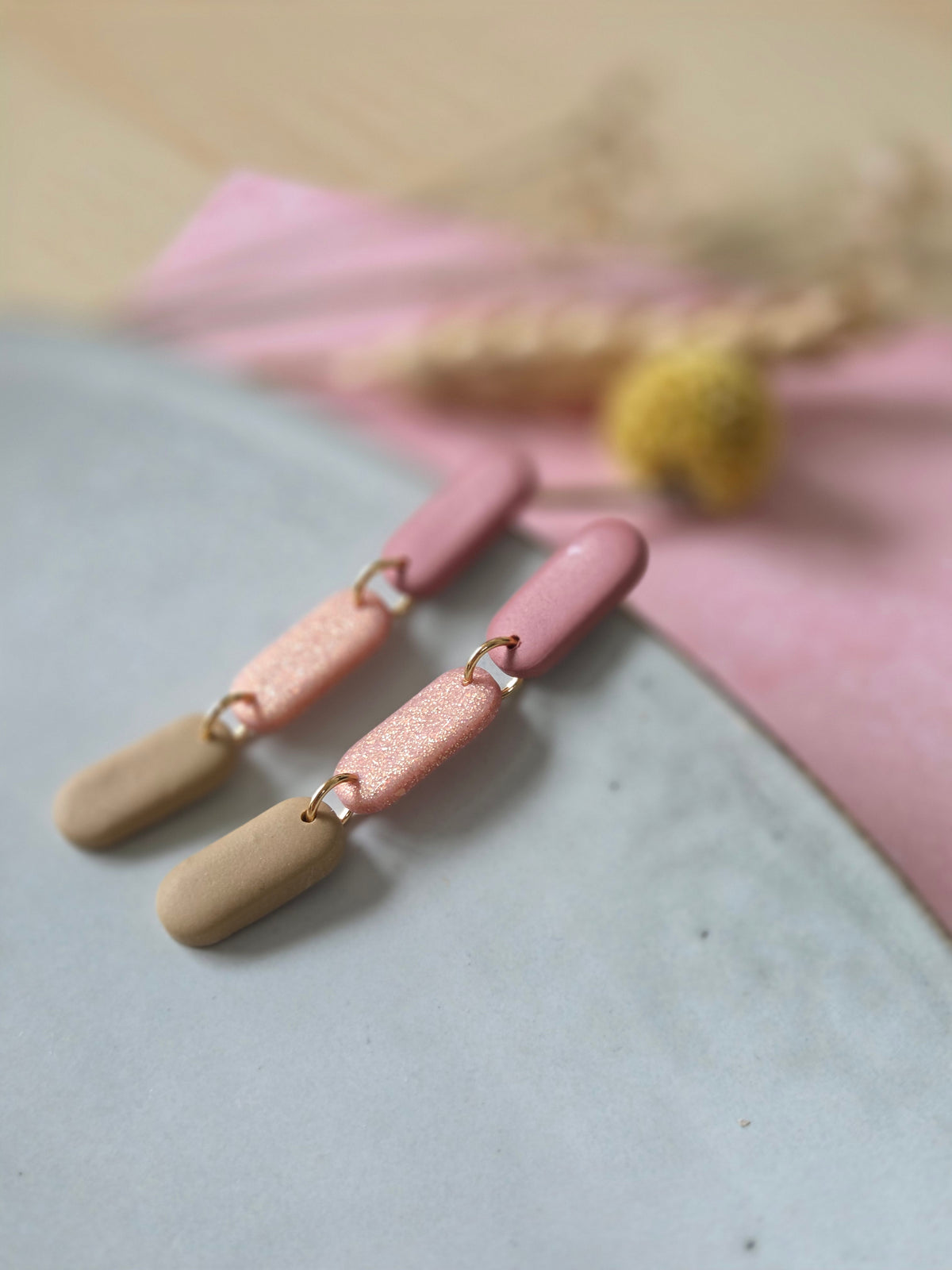 Oorbellen bestaand uit 3 ovalen hangers in oud-roze, glinsterend roze en zand kleur met gouden ringetjes.