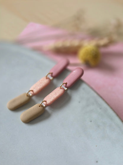 Oorbellen bestaand uit 3 ovalen hangers in oud-roze, glinsterend roze en zand kleur met gouden ringetjes.